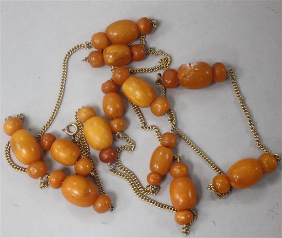 An amber necklace with twelve cluster of three beads on a gilt? metal chain.